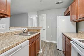 A kitchen with white appliances and brown cabinets.